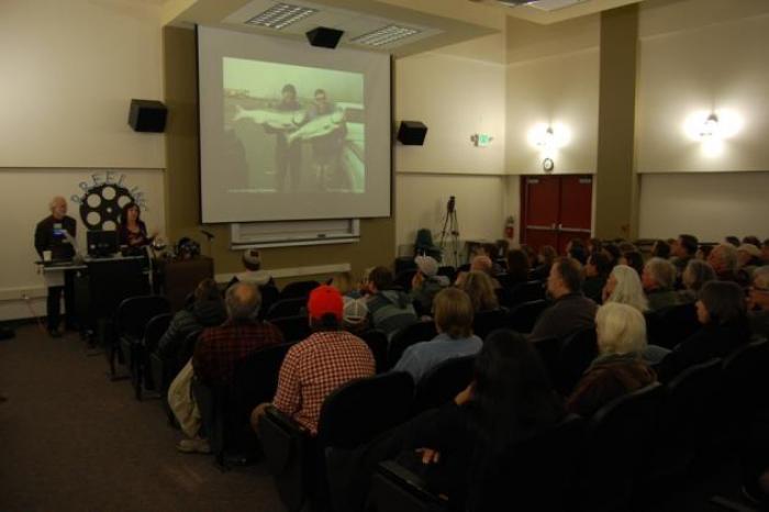 A packed audience watching a local film on a projector